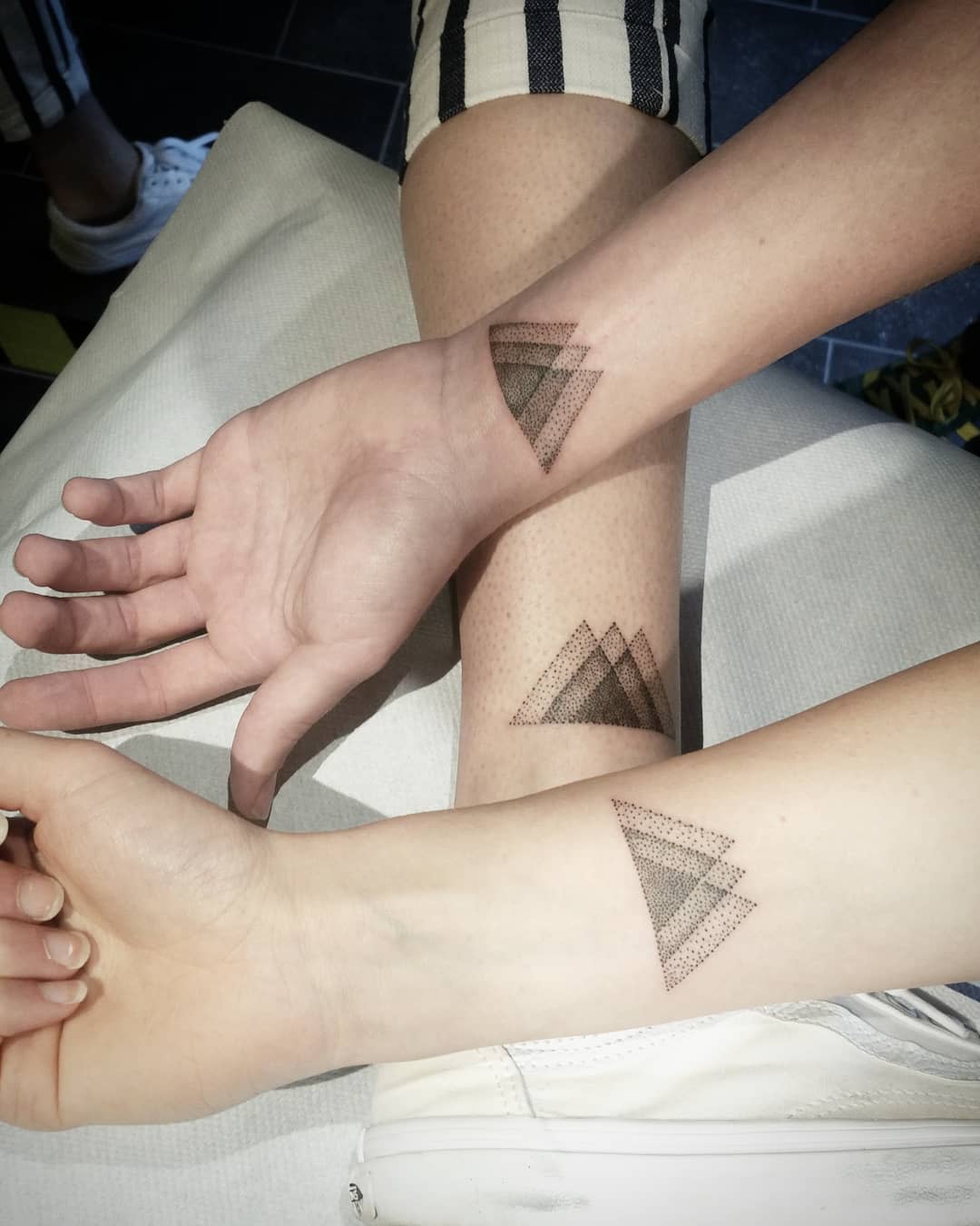 Minimalist geometric tattoos with layered dotted triangles symbolizing unity and connection between individuals